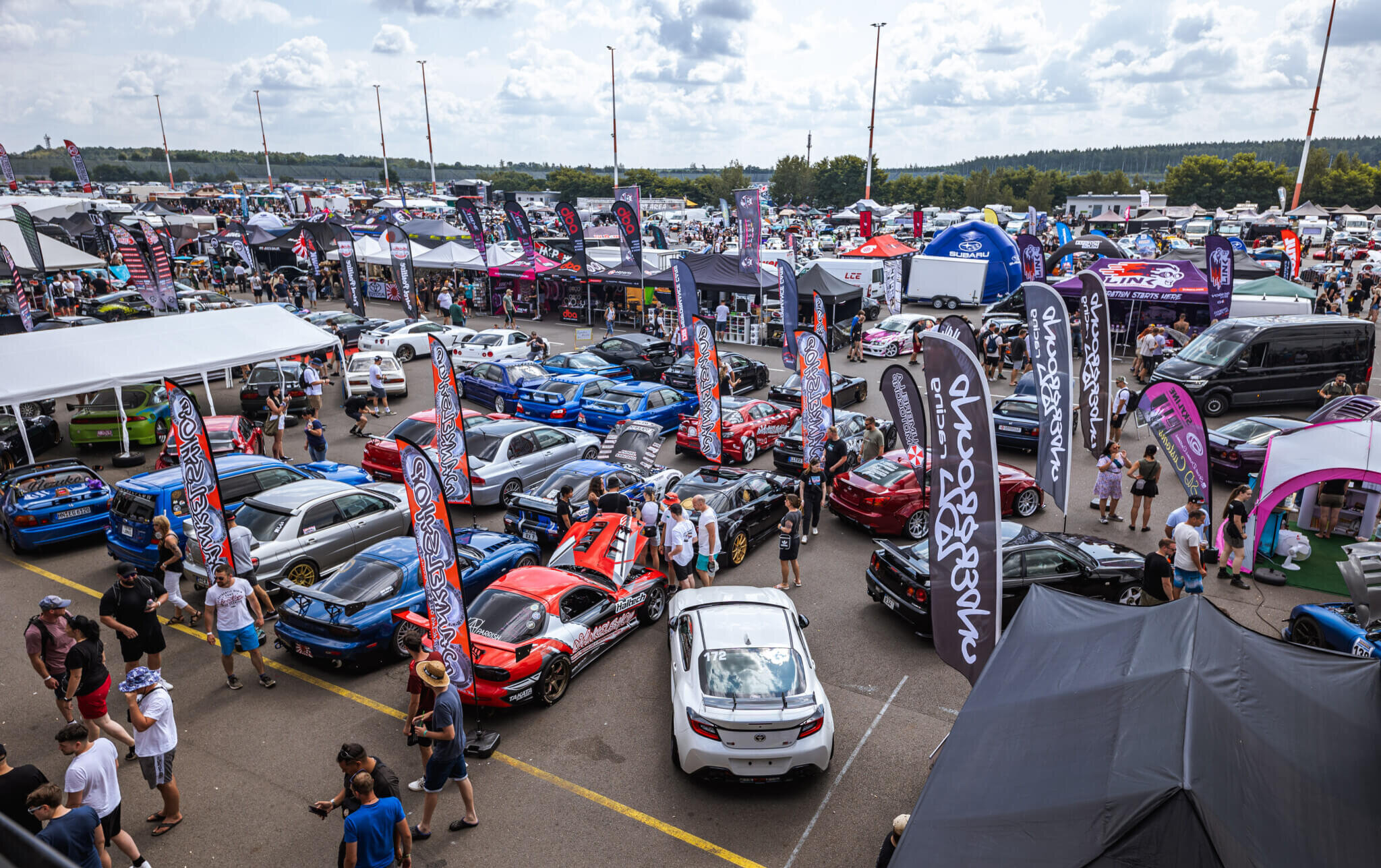 Große Aussteller- und Fahrzeugfläche mit Tuningfahrzeugen und Besuchern beim Reisbrennen am DEKRA Lausitzring