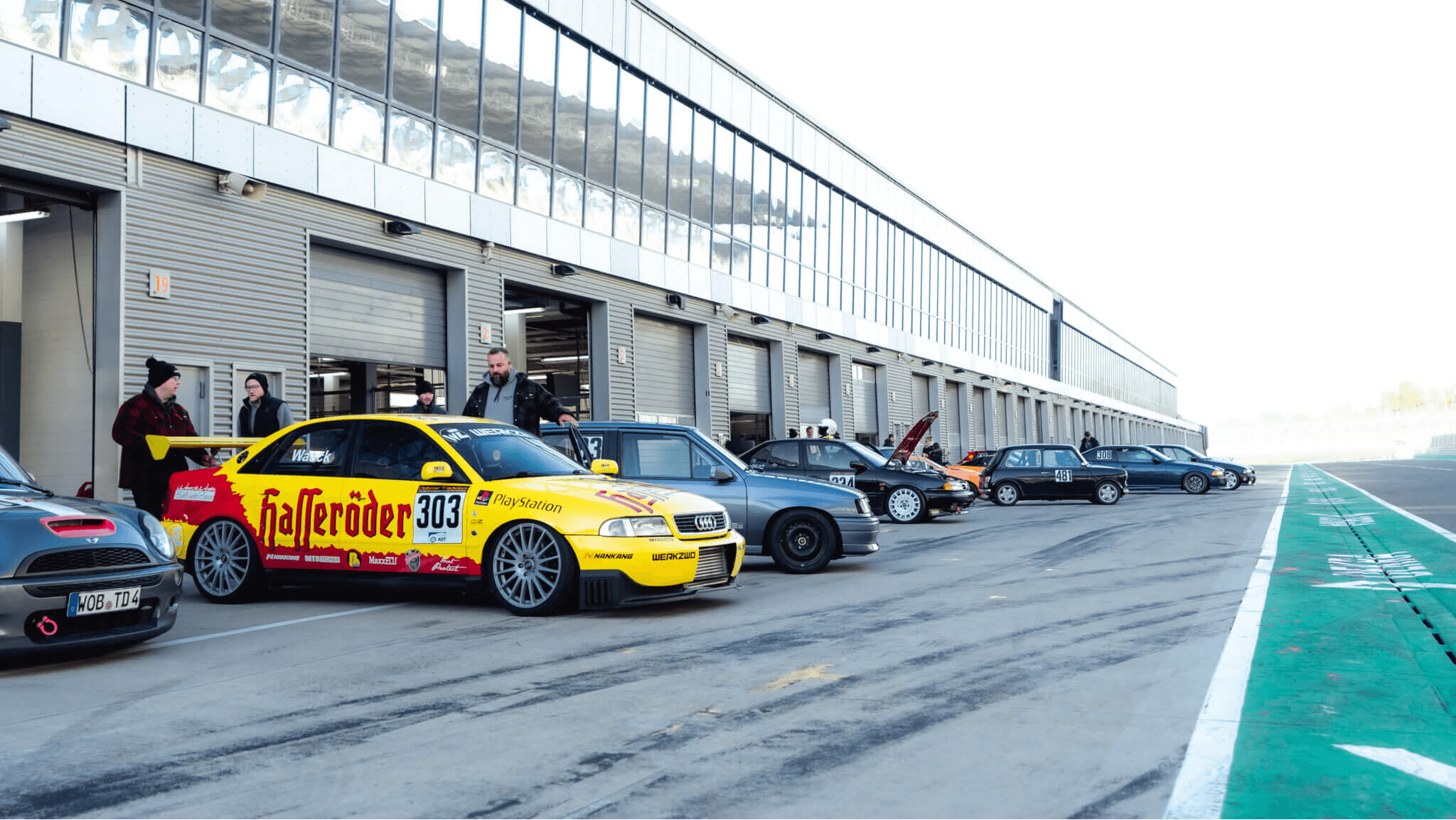 Rennfahrzeuge und Teilnehmer in der Boxengasse des DEKRA Lausitzrings während der Club Days – exklusive Rennstreckenerlebnisse für Automobilclubs, Händler und Motorsport-Fans