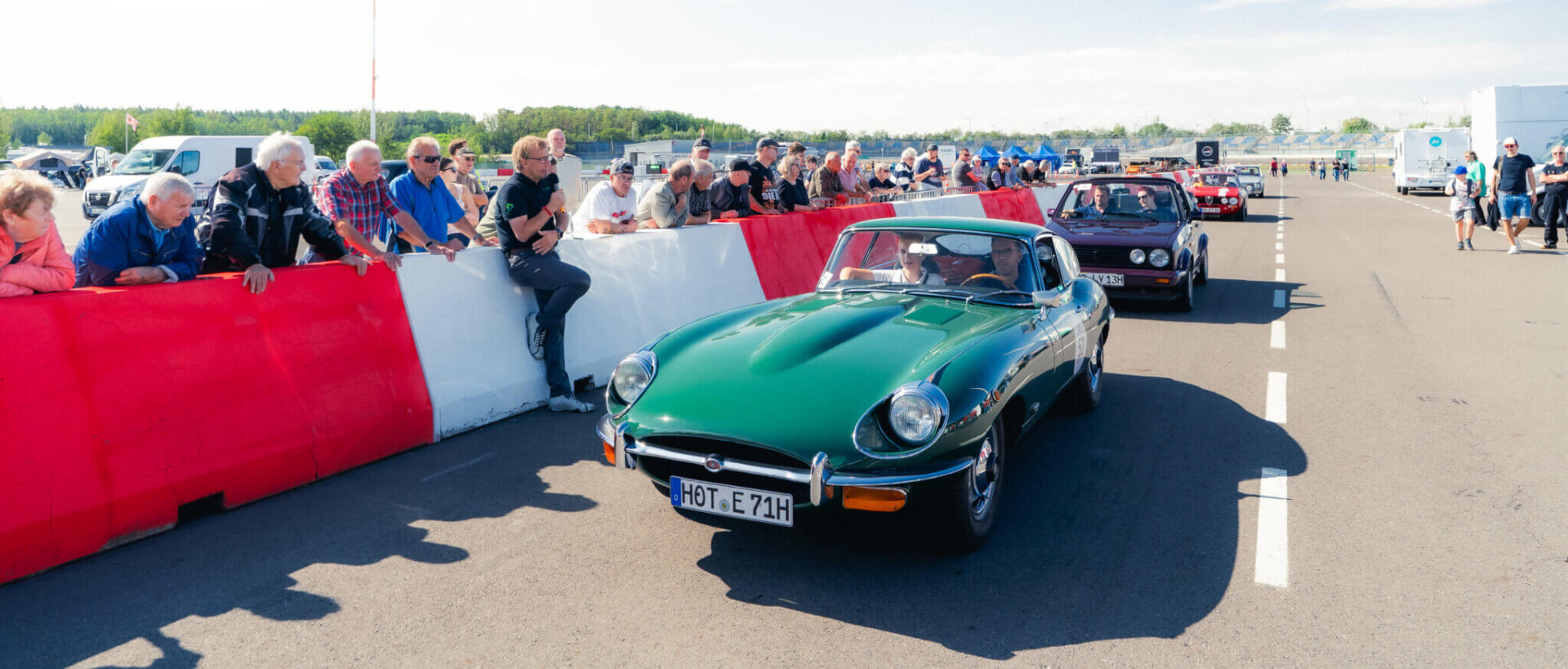 Oldtimer-Ausfahrt mit klassischem Sportwagen und Zuschauern bei den DEKRA Klassik Tagen